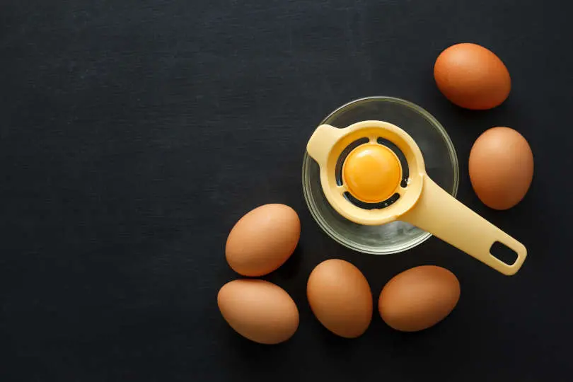 Household egg yolk separator on a glass bowl