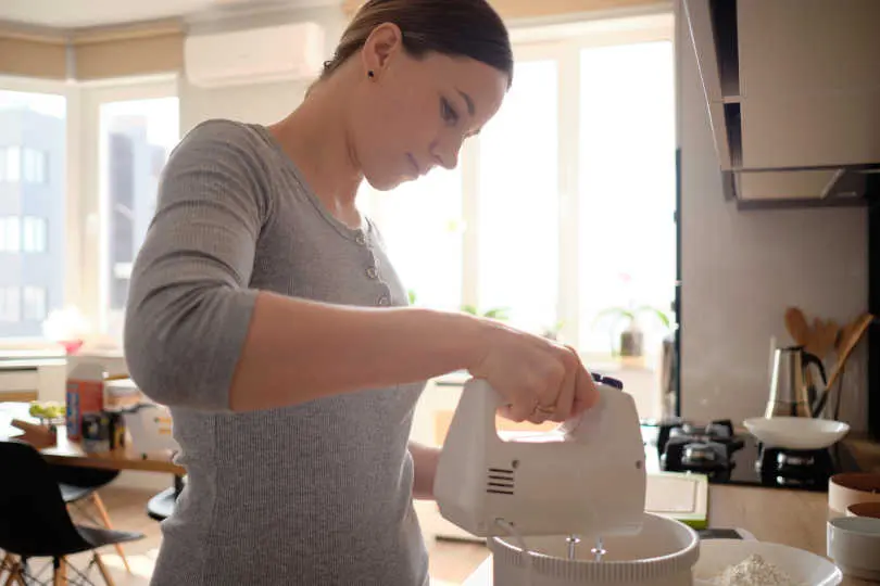 Young woman mixing egg using electric egg beater